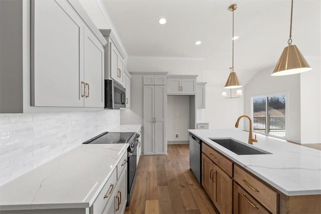 kitchen with a sink, a kitchen island with sink, wood finished floors, stainless steel appliances, and decorative backsplash