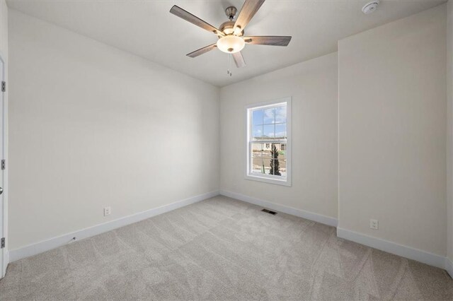 empty room featuring light carpet, visible vents, and baseboards