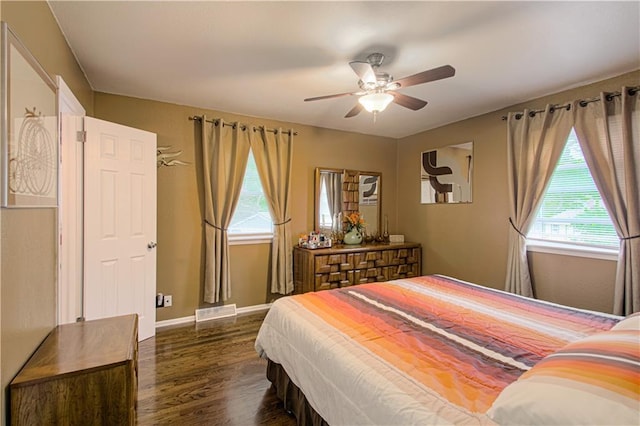 bedroom with dark wood-style flooring, baseboards, visible vents, and multiple windows