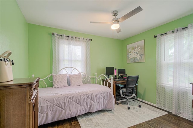 bedroom with a ceiling fan, wood finished floors, and baseboards