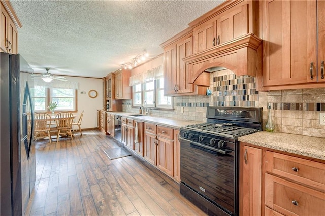763 J Hwy, Peculiar, MO 64078 - kitchen featuring black appliances, a ceiling fan, wood-type flooring, baseboards, and tasteful backsplash