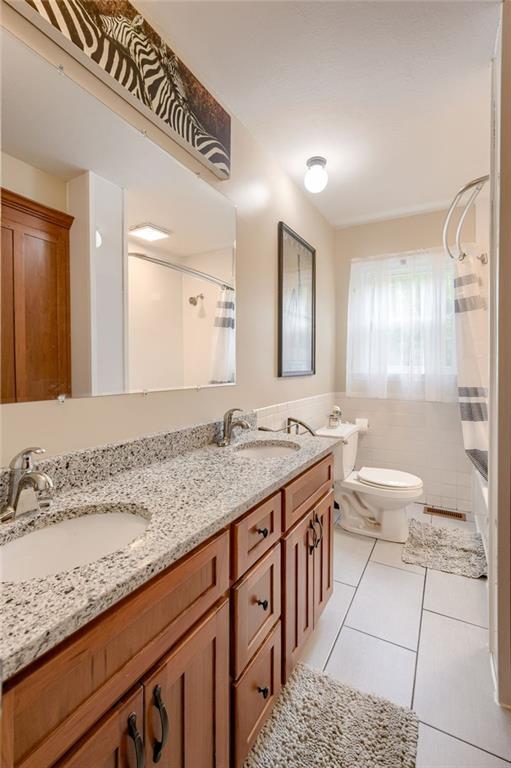 763 J Hwy, Peculiar, MO 64078 - full bathroom featuring tile patterned floors, double vanity, toilet, and shower / bathtub combination with curtain