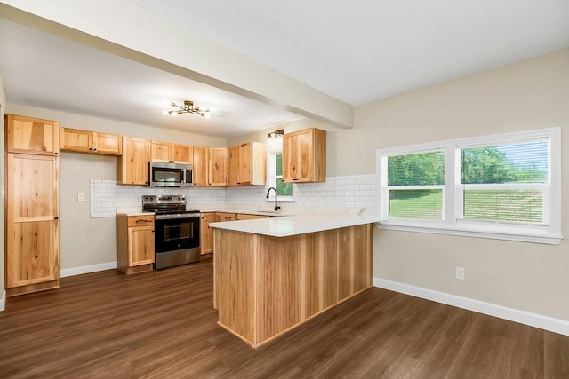2308 NW 53rd Ter, Kansas City, MO 64151 - kitchen featuring stainless steel appliances, a peninsula, baseboards, and dark wood-style floors
