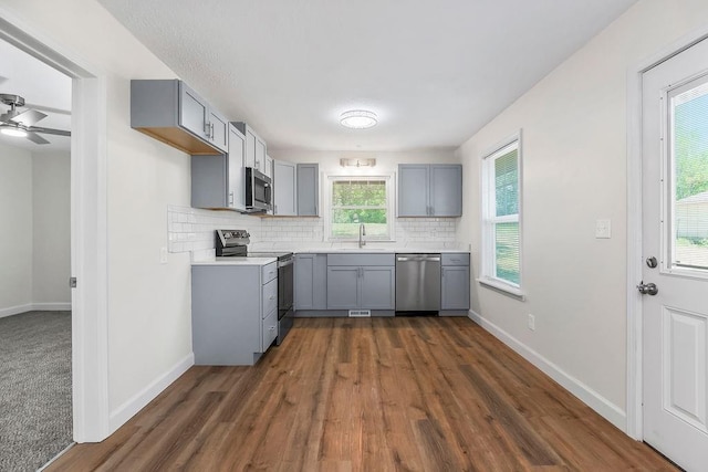 2308 NW 53rd Ter, Kansas City, MO 64151 - kitchen featuring appliances with stainless steel finishes, gray cabinets, tasteful backsplash, dark wood-style flooring, and a sink