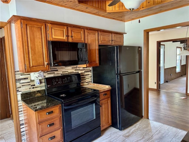 3804 S Drumm Ave, Independence, MO 64055 - kitchen with dark stone counters, backsplash, ceiling fan, brown cabinetry, and black appliances