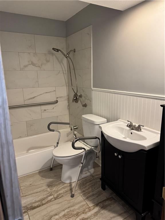 3804 S Drumm Ave, Independence, MO 64055 - full bath with toilet, vanity, bathtub / shower combination, and a wainscoted wall