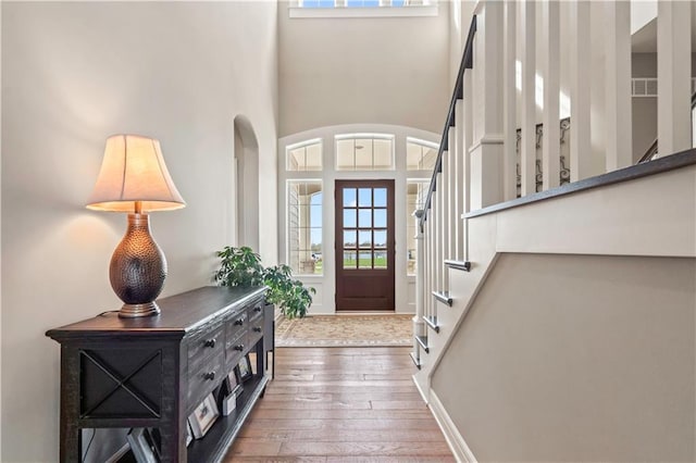 entryway featuring arched walkways, a high ceiling, wood-type flooring, and stairway