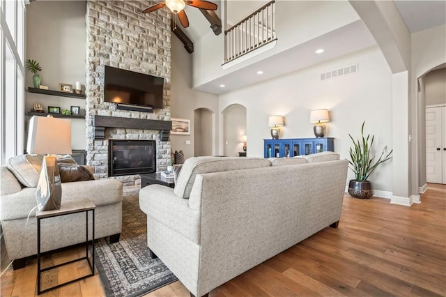 living room featuring visible vents, a ceiling fan, arched walkways, and wood finished floors