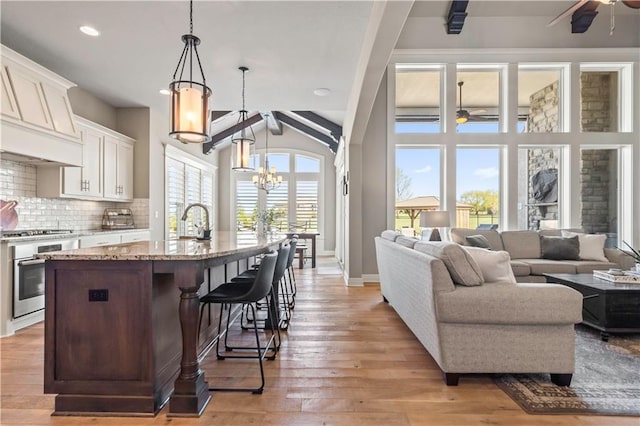 kitchen with stainless steel appliances, white cabinets, ceiling fan with notable chandelier, and backsplash