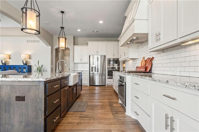 kitchen with custom exhaust hood, a sink, dark brown cabinetry, white cabinetry, and stainless steel appliances