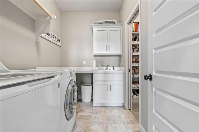 washroom featuring a sink, washing machine and clothes dryer, and cabinet space