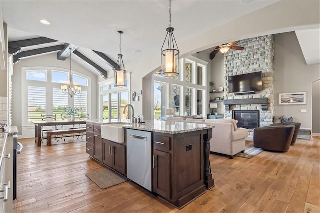 kitchen with dark brown cabinetry, light wood-style floors, stainless steel dishwasher, ceiling fan with notable chandelier, and a sink