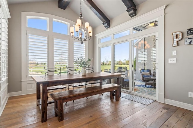 dining room featuring a wealth of natural light, light wood-type flooring, a notable chandelier, and baseboards