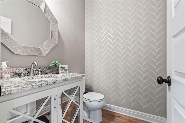 bathroom featuring vanity, baseboards, toilet, and wood finished floors