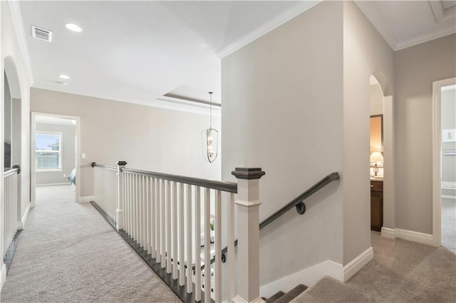 corridor with visible vents, arched walkways, ornamental molding, an upstairs landing, and carpet