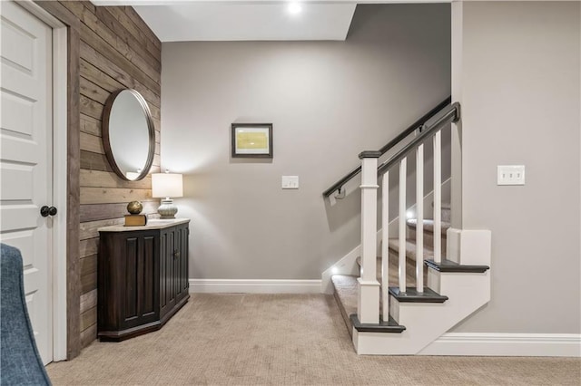 staircase with wooden walls, baseboards, and carpet