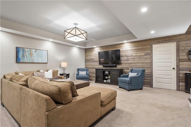 living room with light carpet, recessed lighting, wood walls, visible vents, and a tray ceiling