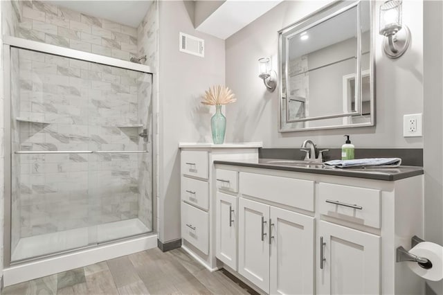 full bathroom with visible vents, a stall shower, wood finished floors, and vanity