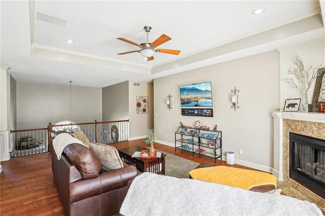 living room with ceiling fan, a raised ceiling, recessed lighting, wood finished floors, and ornamental molding