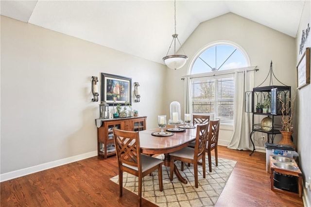 dining area featuring baseboards, wood finished floors, and vaulted ceiling