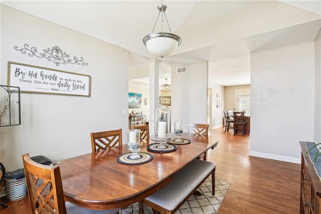 dining space with decorative columns, visible vents, vaulted ceiling, wood finished floors, and baseboards
