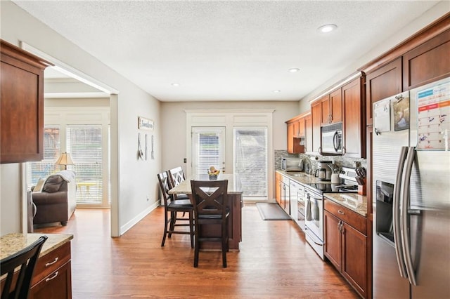 kitchen with a sink, appliances with stainless steel finishes, wood finished floors, and a wealth of natural light