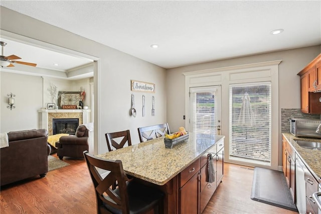 kitchen with a glass covered fireplace, a center island, a kitchen bar, and light wood-style flooring