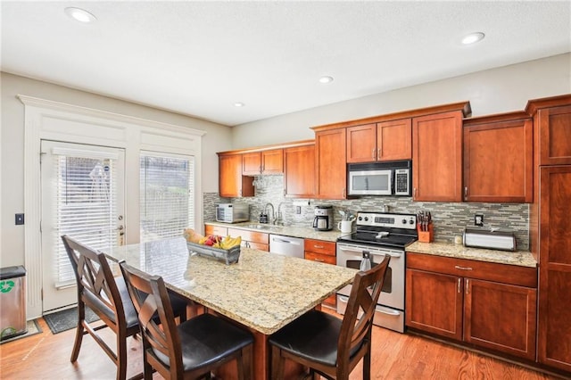 kitchen with a sink, decorative backsplash, appliances with stainless steel finishes, and a breakfast bar
