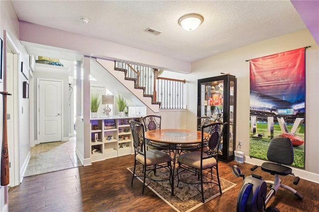 dining space with stairway, a textured ceiling, wood finished floors, and visible vents