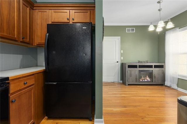 2118 NE 107th Ter, Kansas City, MO 64155 - kitchen featuring visible vents, light countertops, freestanding refrigerator, crown molding, and brown cabinetry