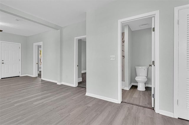 unfurnished bedroom featuring baseboards, connected bathroom, and wood finished floors