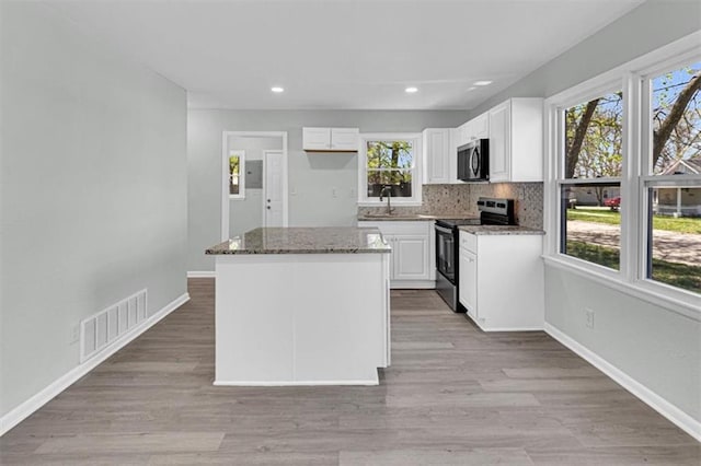 kitchen featuring visible vents, a center island, stone countertops, and stainless steel appliances