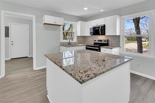 kitchen featuring light wood-style flooring, white cabinetry, light stone countertops, electric stove, and a sink