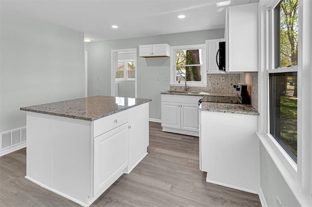 kitchen with range, stone counters, a sink, and visible vents