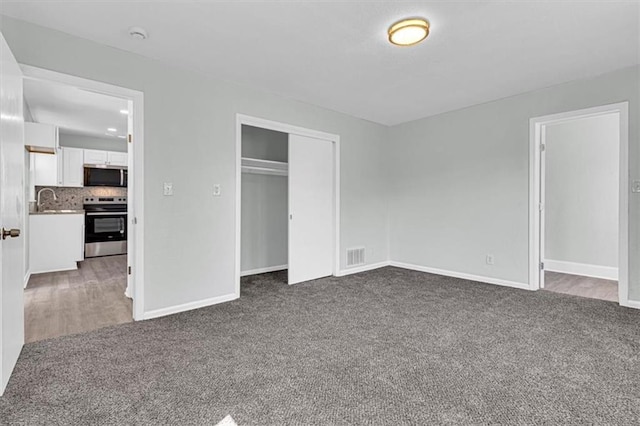 unfurnished bedroom with baseboards, visible vents, a closet, and dark carpet