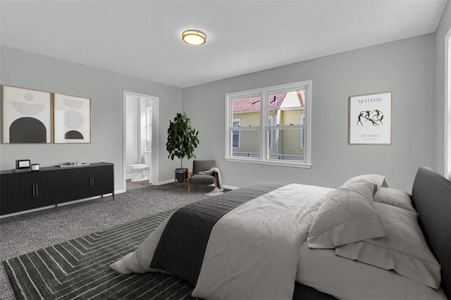 carpeted bedroom featuring ensuite bathroom and baseboards