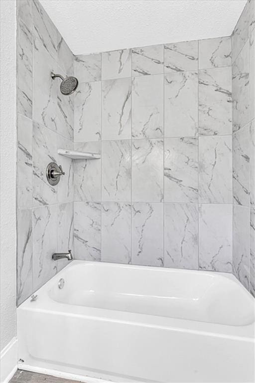 full bath with a textured ceiling and shower / bathtub combination