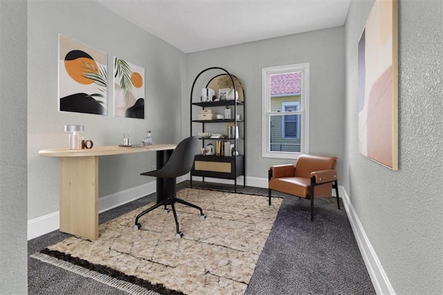 carpeted office featuring a textured wall and baseboards
