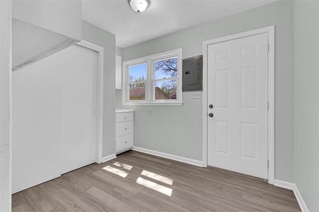 foyer entrance featuring a textured ceiling, wood finished floors, baseboards, and electric panel