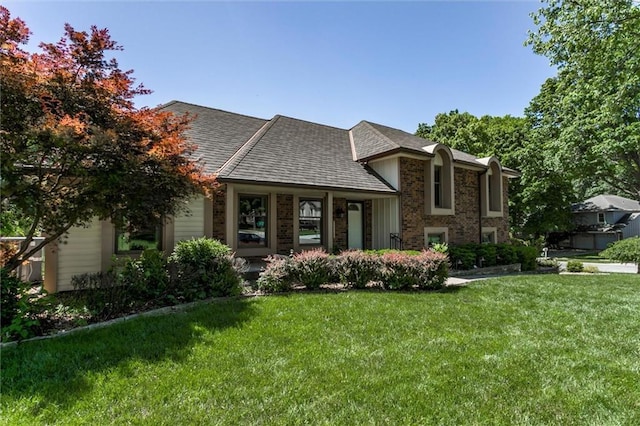 12253 W 104th St, Lenexa, KS 66215 - view of front of house with a front yard, a shingled roof, and brick siding