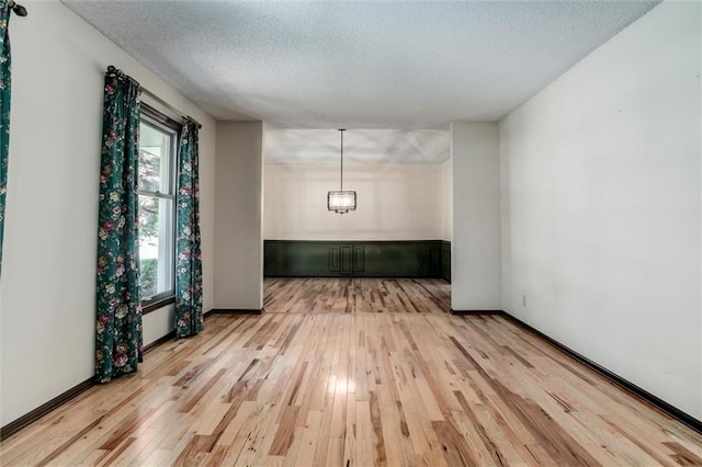 12253 W 104th St, Lenexa, KS 66215 - empty room featuring light wood finished floors, a textured ceiling, and baseboards