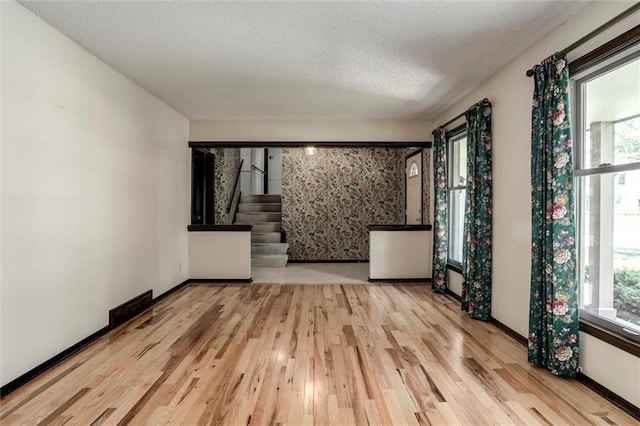12253 W 104th St, Lenexa, KS 66215 - empty room with wood finished floors, healthy amount of natural light, stairway, a textured ceiling, and baseboards