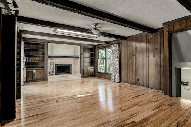 12253 W 104th St, Lenexa, KS 66215 - unfurnished living room with a textured ceiling, wood-type flooring, wooden walls, ceiling fan, and beamed ceiling