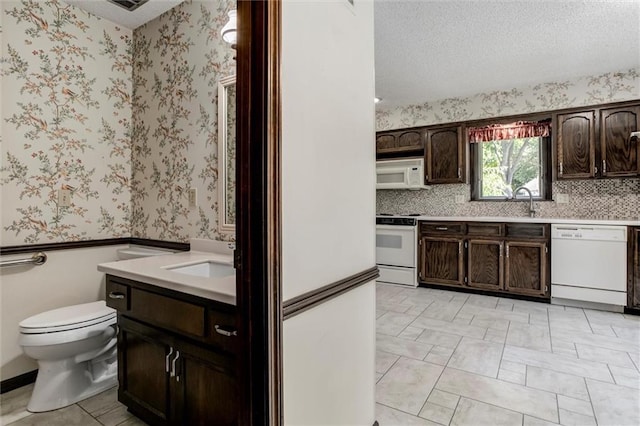 12253 W 104th St, Lenexa, KS 66215 - kitchen with white appliances, a sink, dark brown cabinets, light countertops, and wallpapered walls