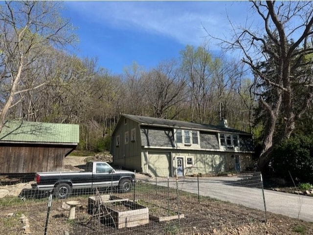 view of outbuilding featuring a garden, fence, and concrete driveway