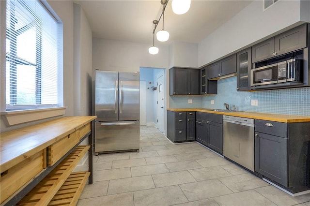 220-222 W Armour Blvd, Kansas City, MO 64111 - kitchen featuring decorative backsplash, light tile patterned floors, a sink, butcher block counters, and stainless steel appliances