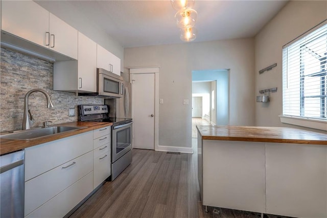 220-222 W Armour Blvd, Kansas City, MO 64111 - kitchen featuring appliances with stainless steel finishes, a sink, dark wood finished floors, wooden counters, and tasteful backsplash