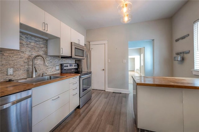 220-222 W Armour Blvd, Kansas City, MO 64111 - kitchen featuring appliances with stainless steel finishes, a sink, wood counters, dark wood finished floors, and backsplash