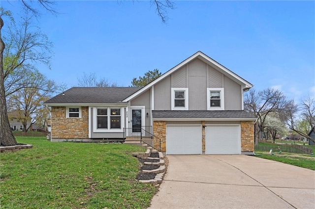 split level home featuring stone siding, an attached garage, driveway, and a front lawn