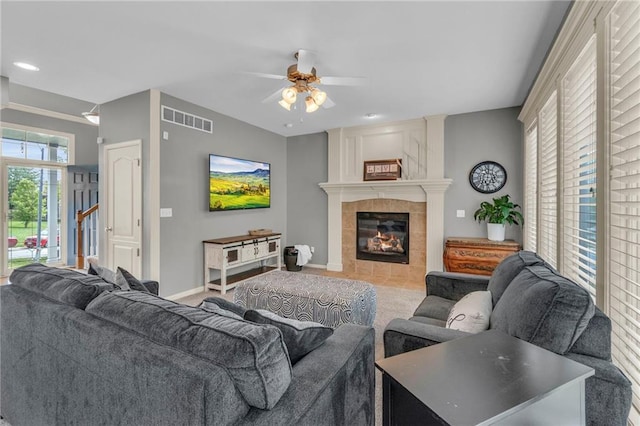 living area featuring visible vents, baseboards, a tile fireplace, a ceiling fan, and carpet
